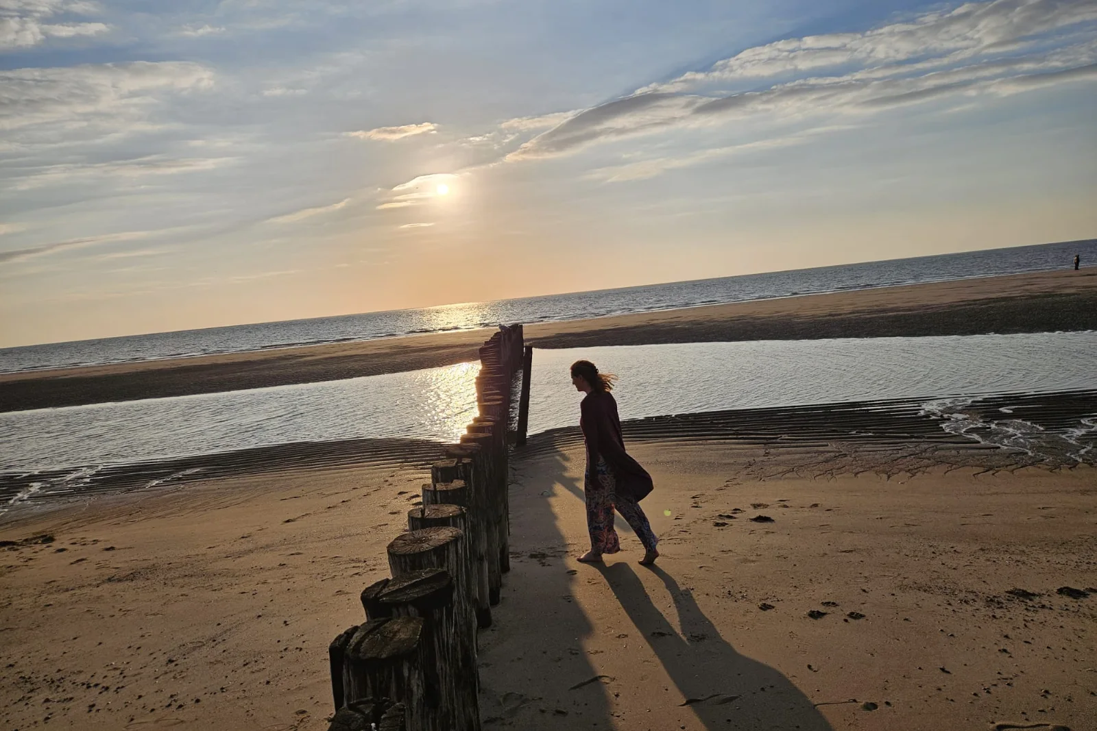 Jorinde loopt ontspannen over het strand bij zonsondergang